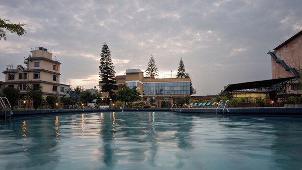 A swimming pool with clear water reflecting surrounding buildings and trees.