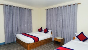 A hotel room with two beds, a wooden headboard, a nightstand, and grey patterned curtains. - Club Bagmati by HSH (Suryabinayak)