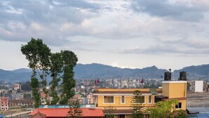 A swimming pool with a curved edge, surrounded by stone steps and potted plants. - Club Bagmati by HSH (Suryabinayak)
