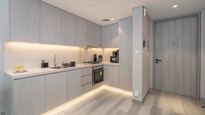 A modern kitchen with light wood cabinetry, a built-in oven, and a stainless steel sink. - StayShort - Amazing 1 Bedroom in Concept 7 JVC Sleeps 2 (Jumeirah Village Circle)