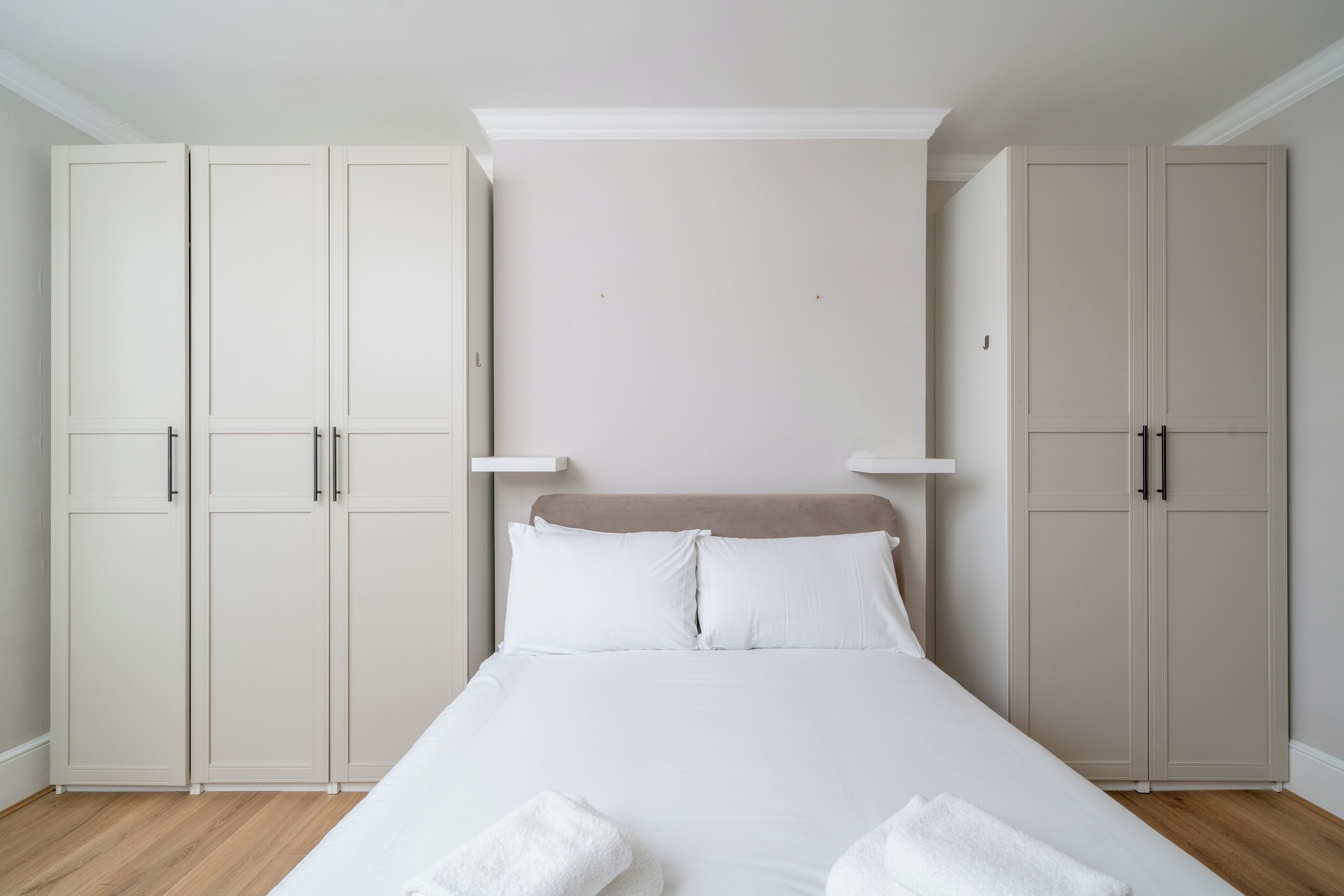 Un dormitorio con una cama, dos armarios y un cabecero.