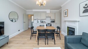 Un salon moderne avec une table à manger, des chaises, un canapé, une cheminée et une cuisine en arrière-plan.