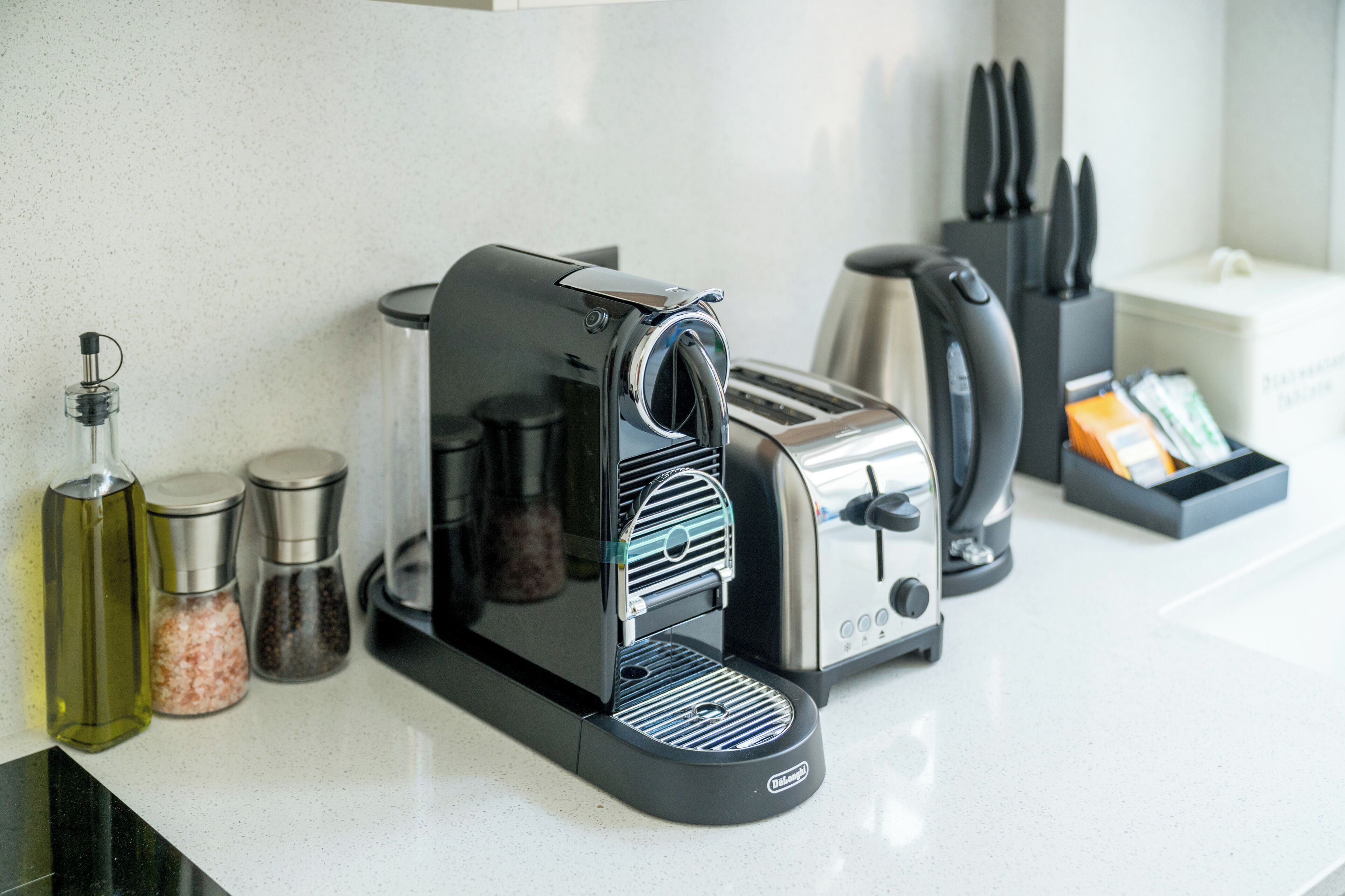A kitchen counter with a coffee maker, toaster, salt and pepper shakers, and a knife block.
