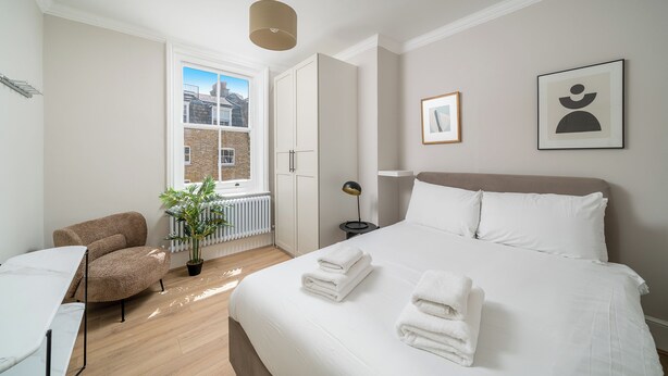 Une chambre d’hôtel moderne avec un grand lit, une chaise, un bureau et une plante en pot.