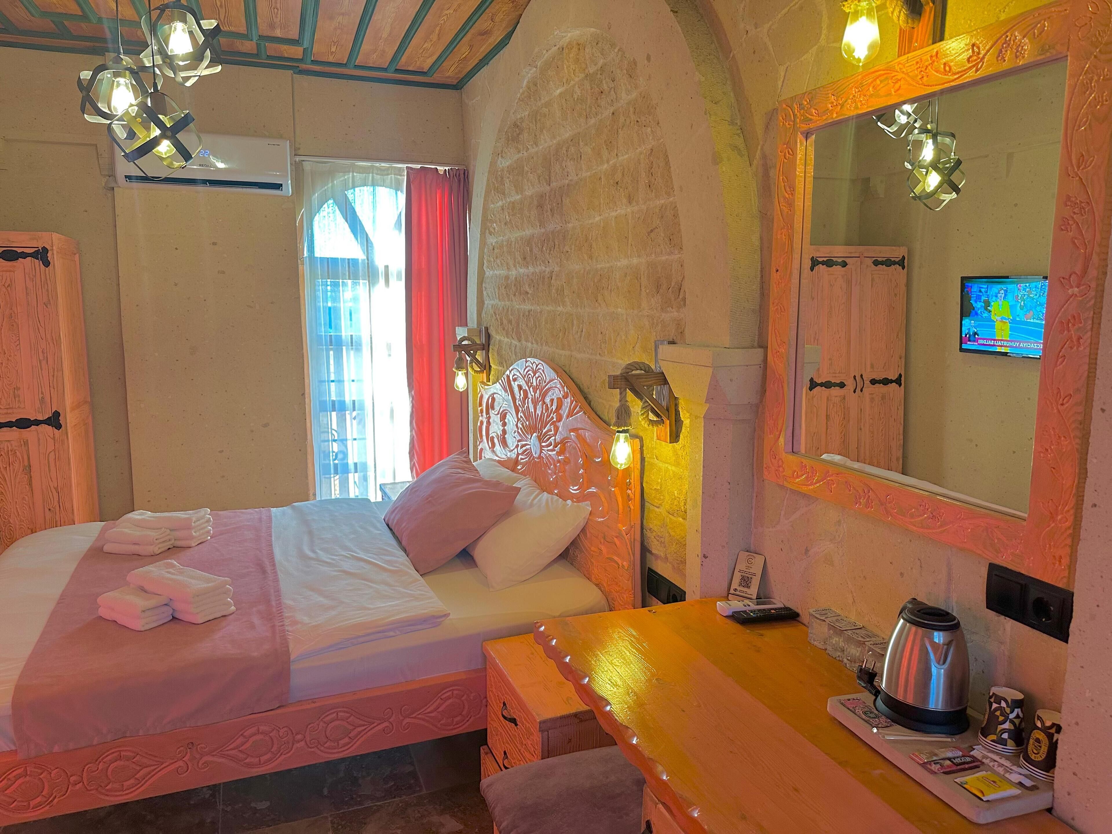 Une chambre d’hôtel avec un lit, une table de chevet en bois, un miroir et un téléviseur.
