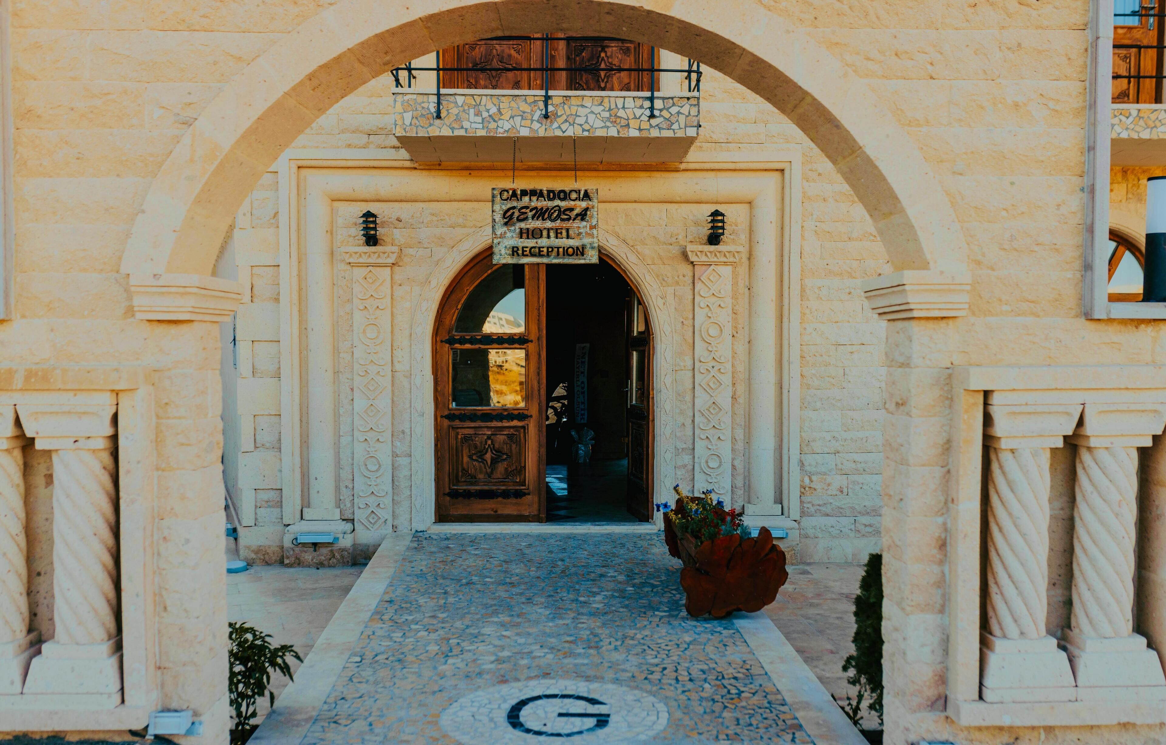 A hotel entrance with an arched doorway, a reception sign, and a mosaic floor.