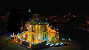 Ein Gebäude mit einer Steinfassade, Rundbogenfenstern und einem grünen Dach.