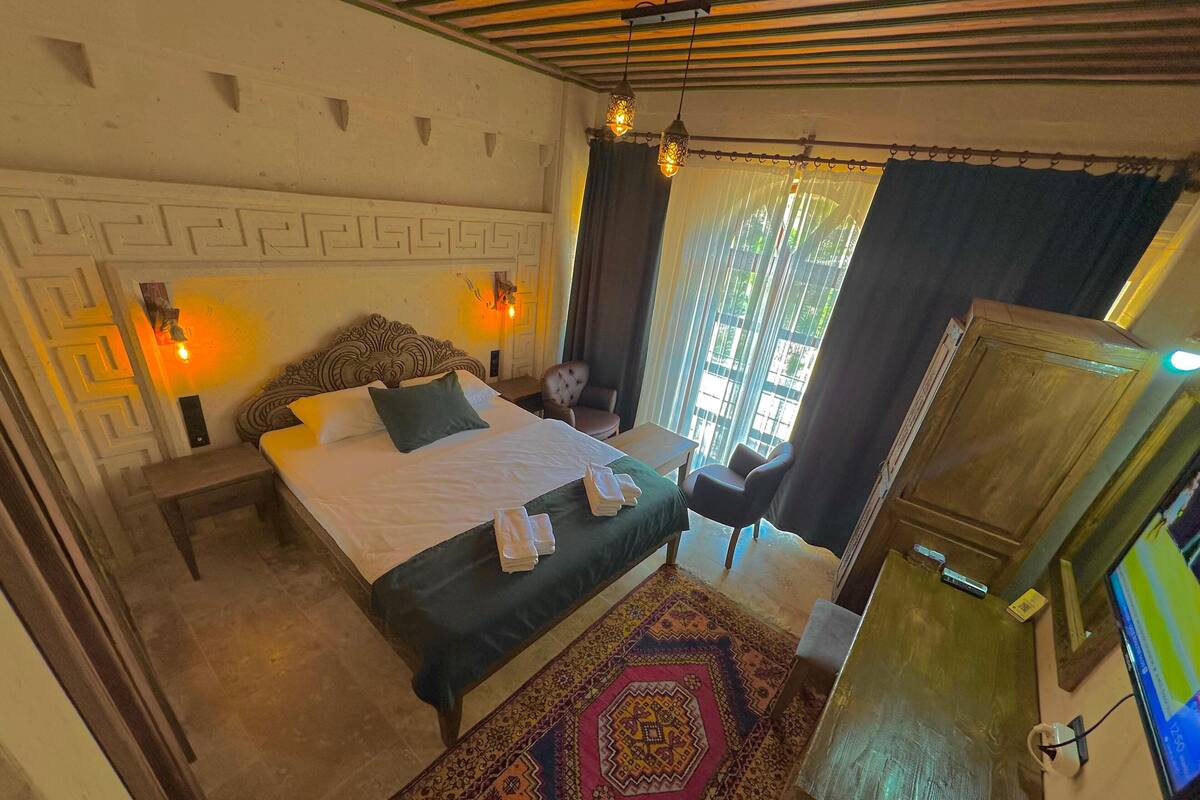Ein Schlafzimmer mit Bett, Nachttisch, Stuhl und Fernseher.