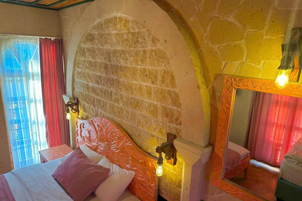 Ein Hotelzimmer mit einem Bett, einem Spiegel und einer Steinwand.