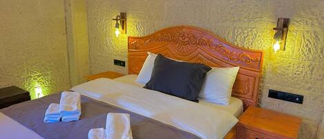 A neatly made bed with a wooden headboard, two bedside tables, and a wall-mounted light fixture.