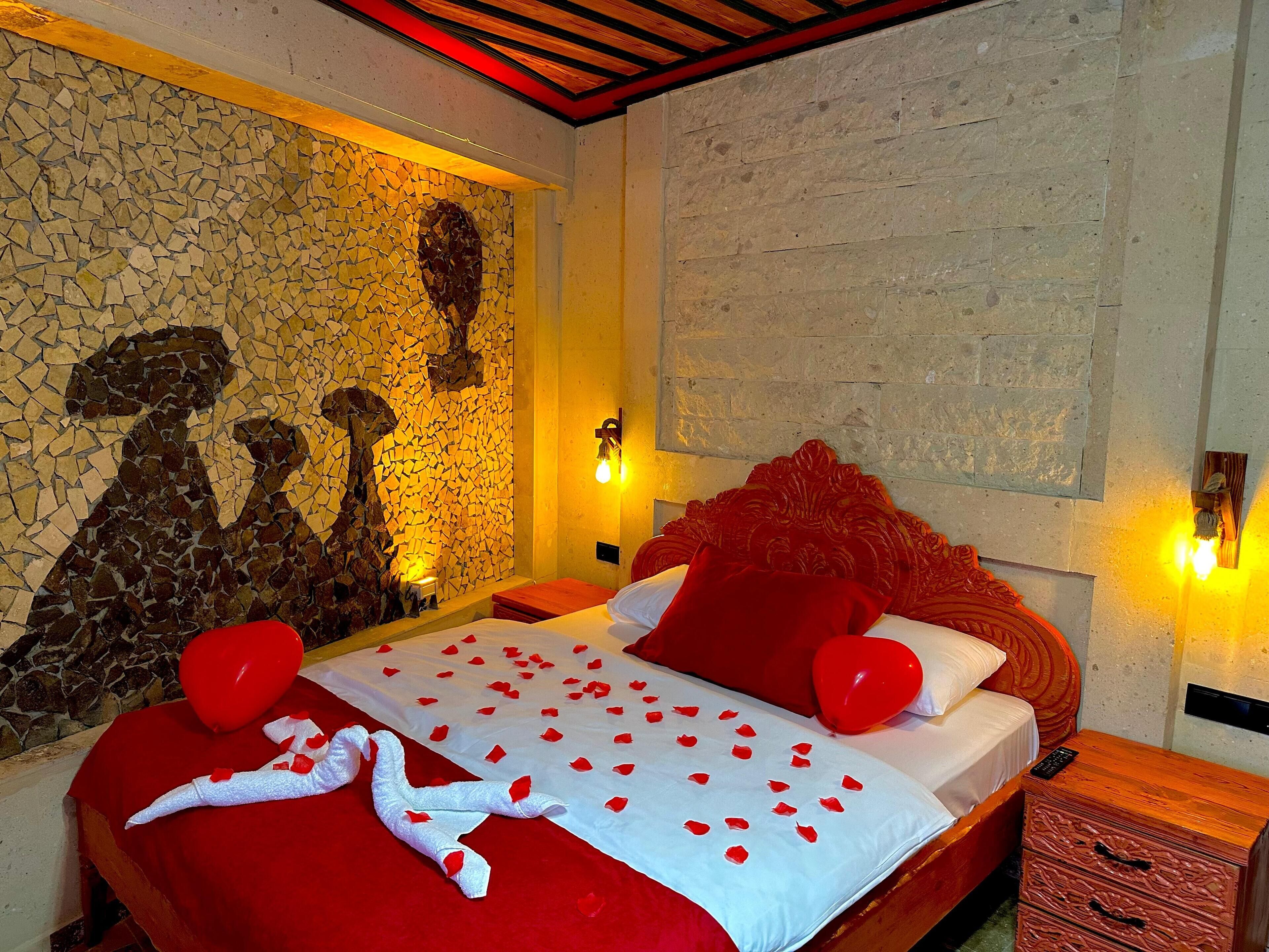 A hotel room with a bed, a stone mosaic wall, and a wooden headboard.
