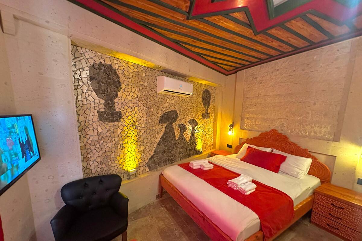 Ein Schlafzimmer mit einem Bett, einem Sessel, einem Fernseher und einer Steinwand.