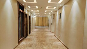 A hallway with a marble floor, recessed lighting, and a view of a room with a curtain. - Hotel Maple Residence (Udaipur)