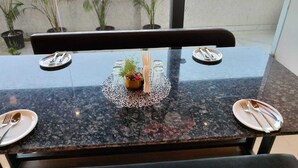 A dining table with a view of a cityscape through a window. - Hotel Maple Residence (Udaipur)