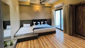 A modern bedroom with a large bed, a ceiling fan, and an air conditioning unit. - Hotel Maple Residence (Udaipur)