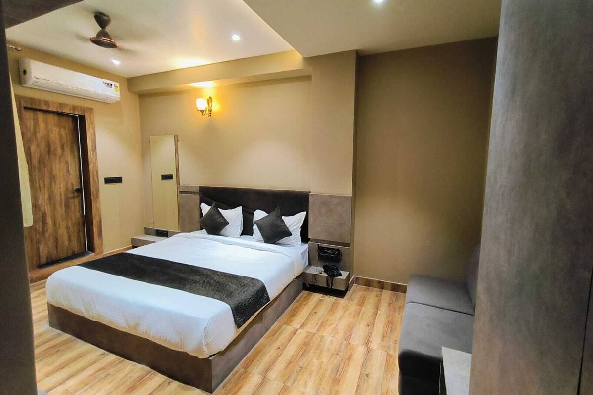 Ein modernes Hotelzimmer mit einem großen Bett, Holzboden, Deckenventilator, Klimaanlage und einem Nachttisch mit Lampe.