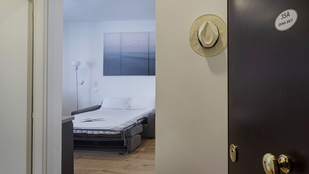 A hotel room with a bed, a nightstand, a lamp, and a wall-mounted artwork.