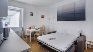 A compact hotel room with a bed, a desk, and a dining table.