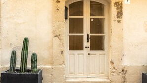 Una porta bianca con un pannello in vetro, il numero 7, e un piccolo cactus in vaso a sinistra.