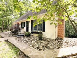 A house with a stone pathway leading to the front door, surrounded by a garden with various plants and a brick column. - Ridgetop Retreat- Minutes from Town, Dog Friendly, Wood Fireplace (Berkeley Springs)