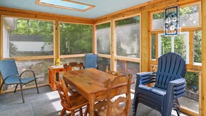 Ein Wintergarten mit Holztisch und -stühlen, großen Fenstern und einer Glasmalerei.