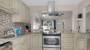 A kitchen with a central island, stainless steel appliances, and light-colored cabinetry. - Pier Atlas (Panama City Beach)