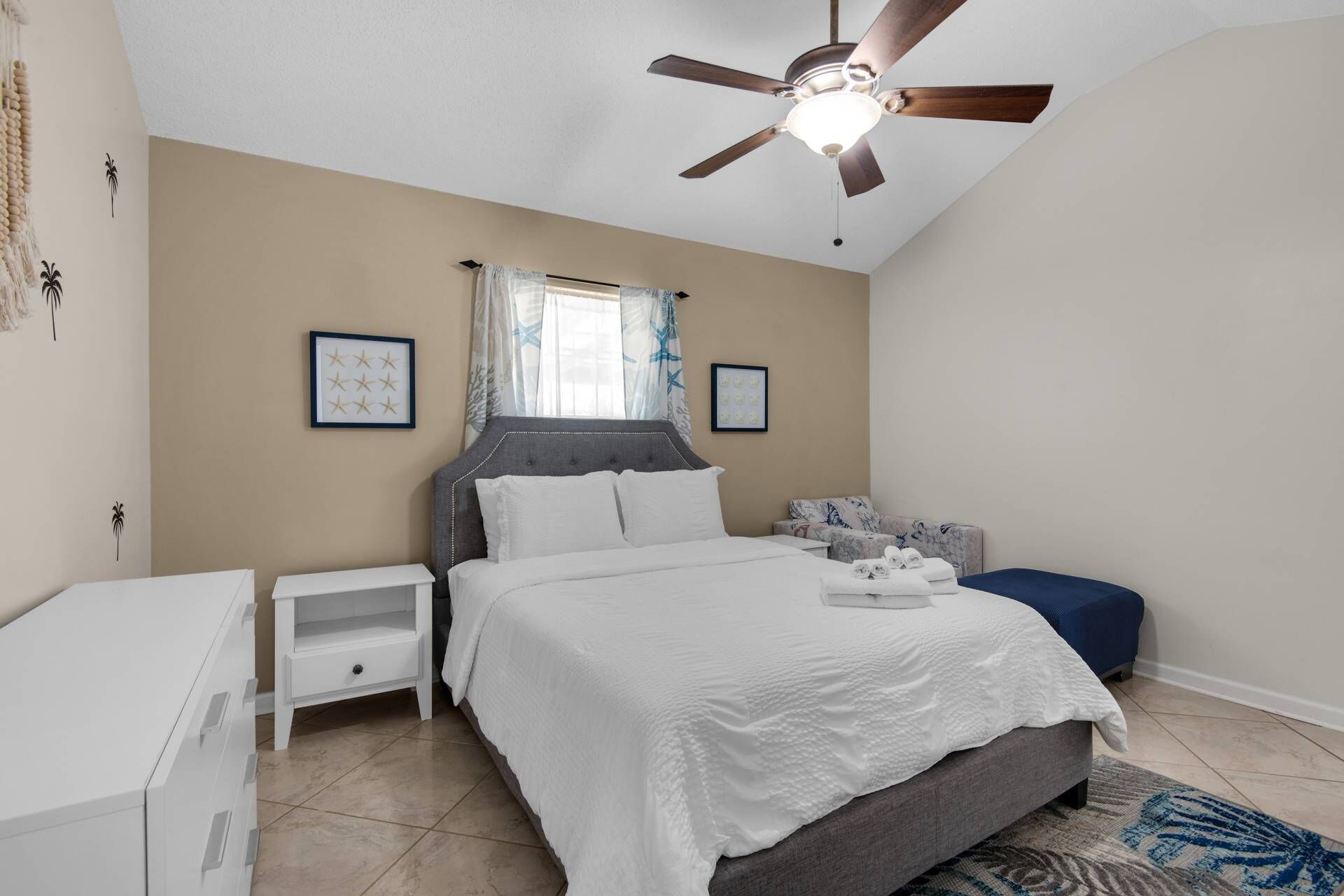 A bedroom with a bed, nightstands, a ceiling fan, and a window with curtains.