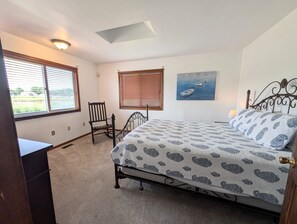Un dormitorio con cama, una silla, un escritorio y una ventana con persianas.
