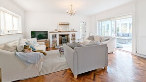 A spacious living room with a fireplace, two sofas, a television, and a large window.
