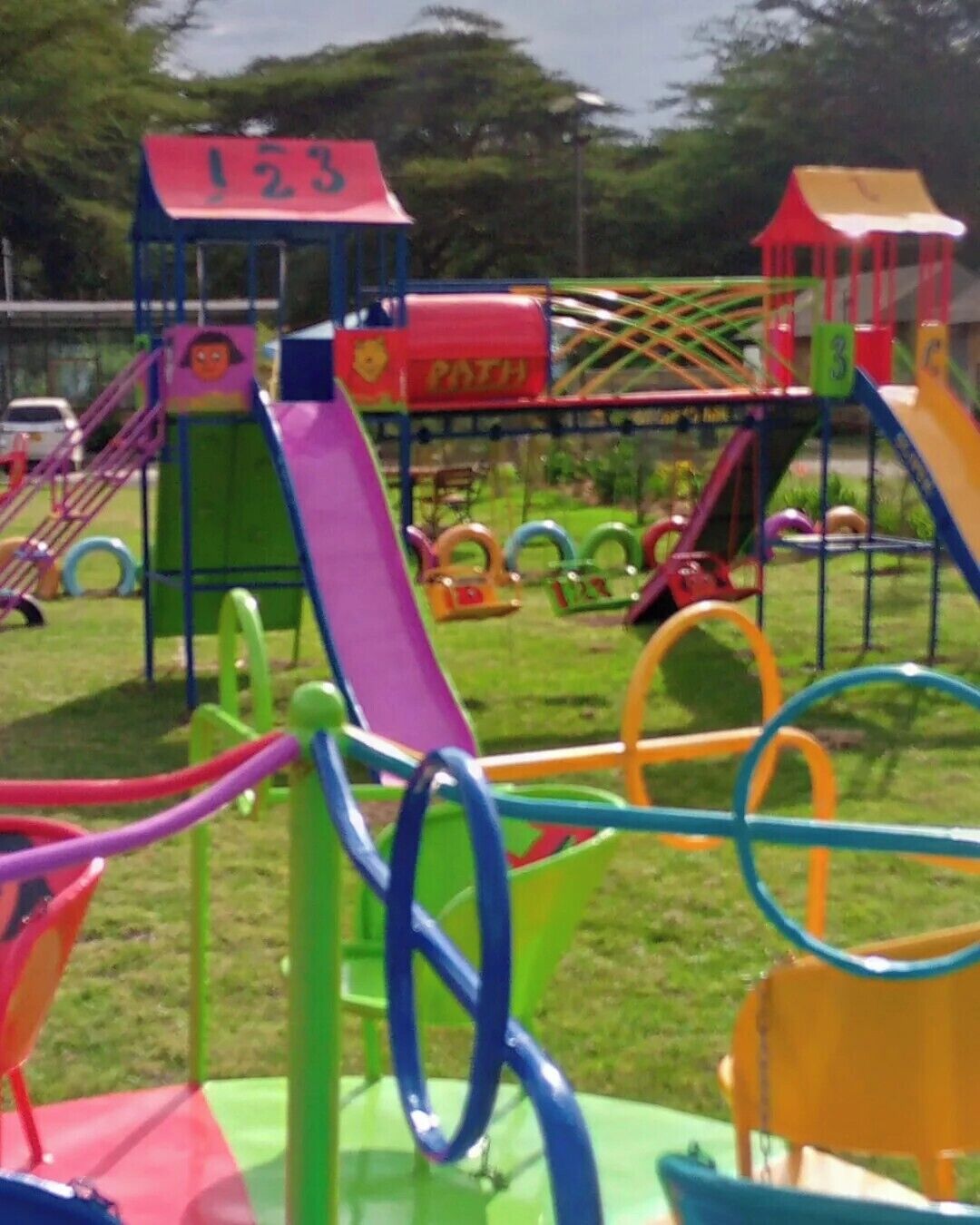 Ein Spielplatz mit verschiedenen bunten Spielgeräten, darunter Rutschen und Schaukeln.