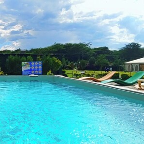 Una piscina con acqua cristallina, circondata da un'area verdeggiante con uno scivolo e sdraio.