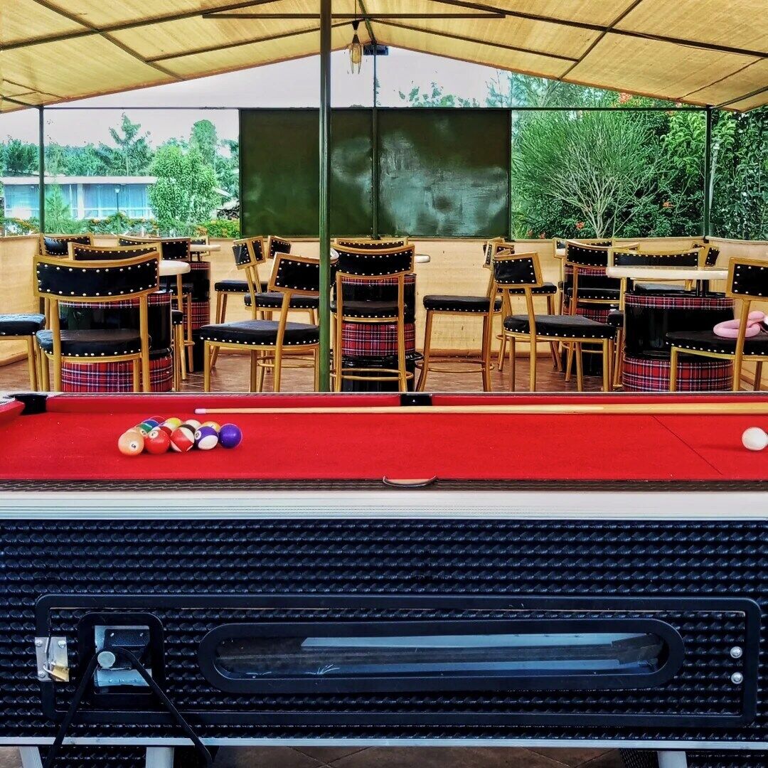 A pool table with chairs and a billiard cue.