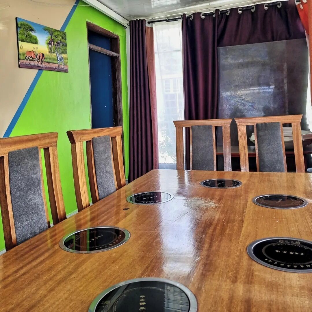 Une salle de conférence avec une table en bois, six chaises et une grande fenêtre avec des rideaux.