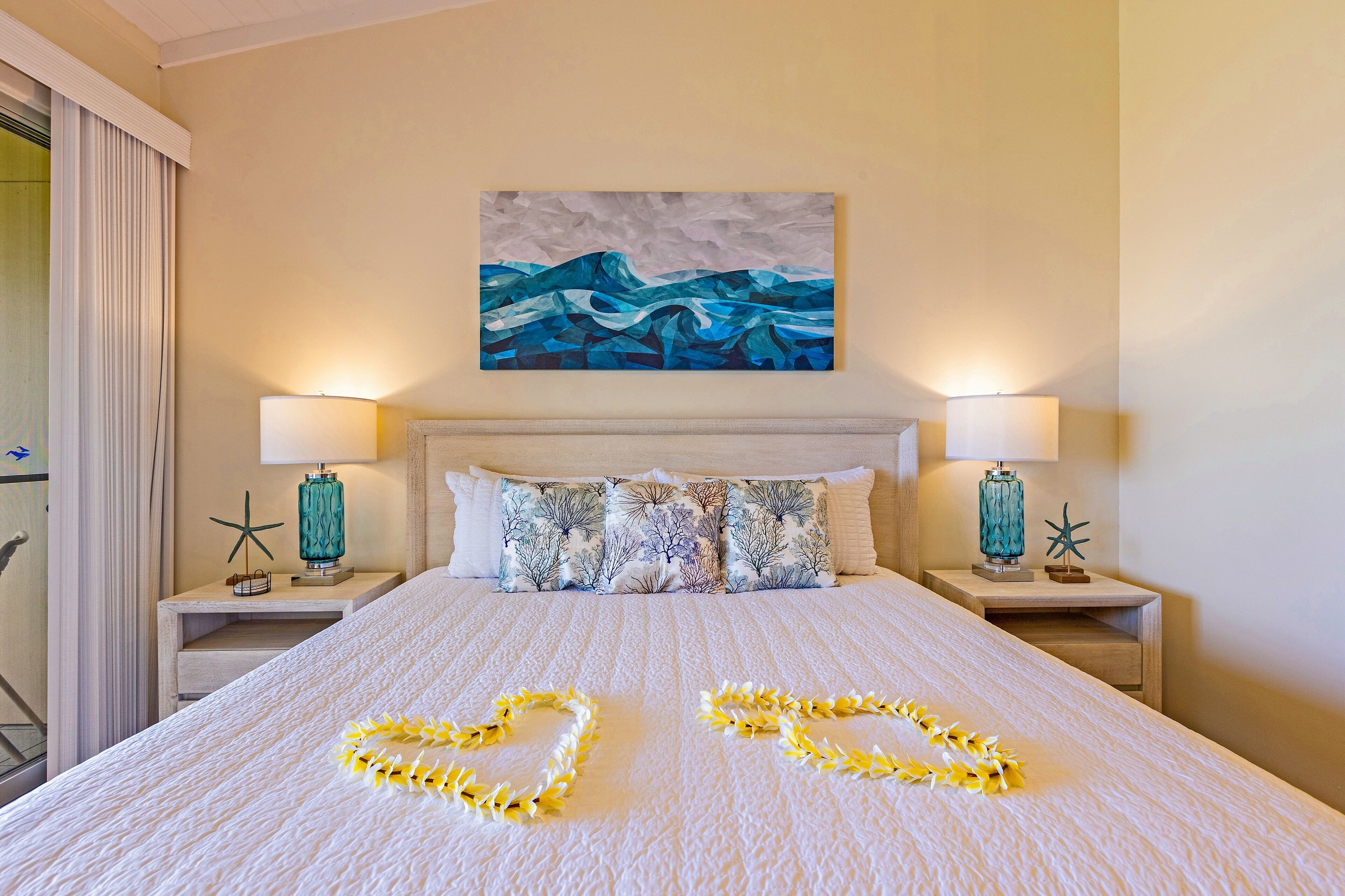 A hotel room with a large bed, two nightstands with lamps, a painting above the bed, and a starfish decoration on one nightstand.