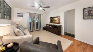 A living room with a sofa, a coffee table, a TV, and a ceiling fan. - Big Island Kona Kai J2 2 Bedroom Condo (Kailua-Kona)