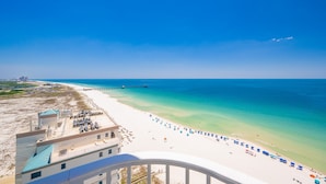 Blick auf einen Strand mit einer Mole, blauem Himmel und weißem Sand.