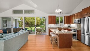 A modern kitchen with wooden cabinets, stainless steel appliances, and a large island. - Kauai 2247 Loke Road 3 Bedroom Home (Koloa)