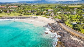 A coastal town with a beach, houses, and mountains in the background. - Kauai 2247 Loke Road 3 Bedroom Home (Koloa)