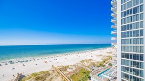 Vista a la playa desde un hotel con piscina y una pasarela de madera.