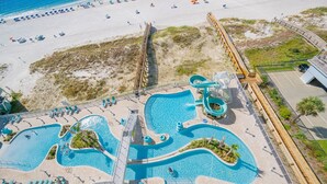 Vista aérea de un resort con una gran piscina, un tobogán acuático y una zona de playa con tumbonas.