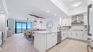 Una cocina moderna con armarios blancos, una isla central y una zona de comedor con vistas.