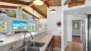 Una cocina moderna con una isla grande, armarios de madera y vistas al océano a través de amplios ventanales.