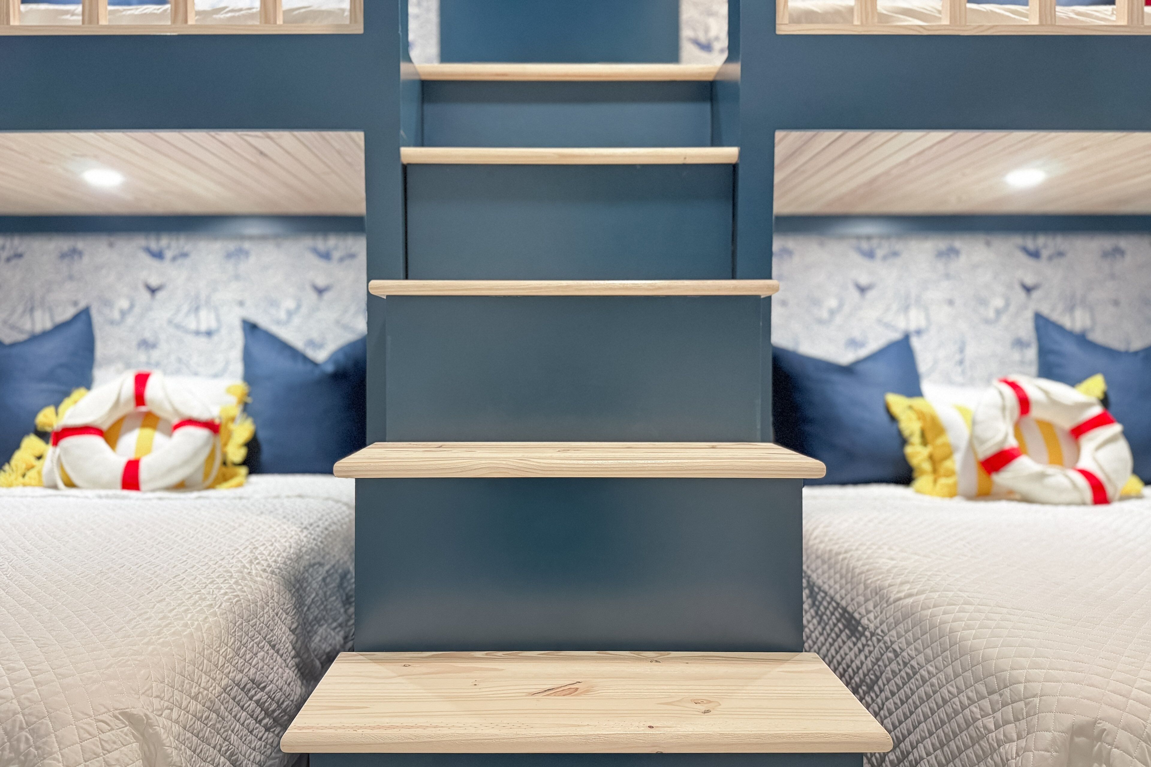 Un dormitorio con una cama, una escalera de madera y un papel tapiz decorado.