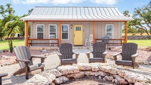 A lodge with a metal roof, a yellow door, and a porch with Adirondack chairs.
