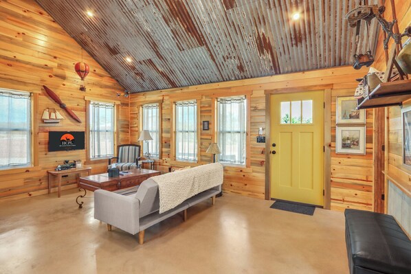 A cozy cabin with wooden walls, a bed, a desk, and a TV.
