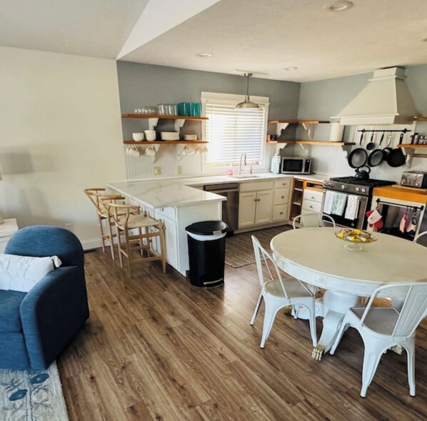 A compact kitchen with a dining area, wooden flooring, and a blue sofa. - Northern Retreat in the Heart of Indian River! (Indian River)