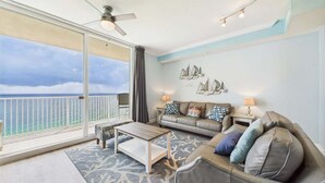 A balcony with a view of the ocean, a sofa, a coffee table, and a ceiling fan. - Skywaves Escape 2503-Stunning Views-Sleeps 5 (Panama City Beach)