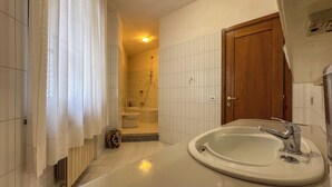 Une salle de bain avec une grande baignoire, des toilettes et une douche.