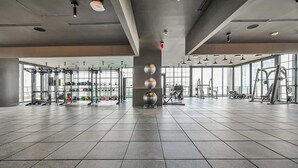 A spacious gym with various exercise equipment, large windows, and a modern design.
