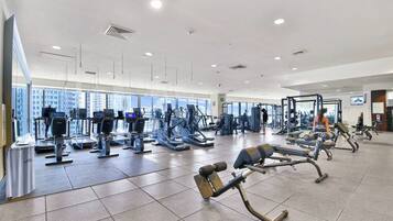 A spacious gym with various exercise machines, large windows, and a modern design.
